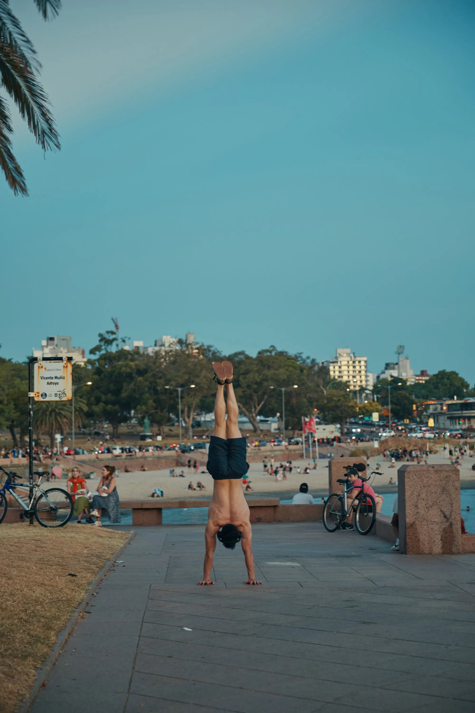 Alguien haciendo la vertical sobre el muro de la Rambla Sur, con la playa detrás