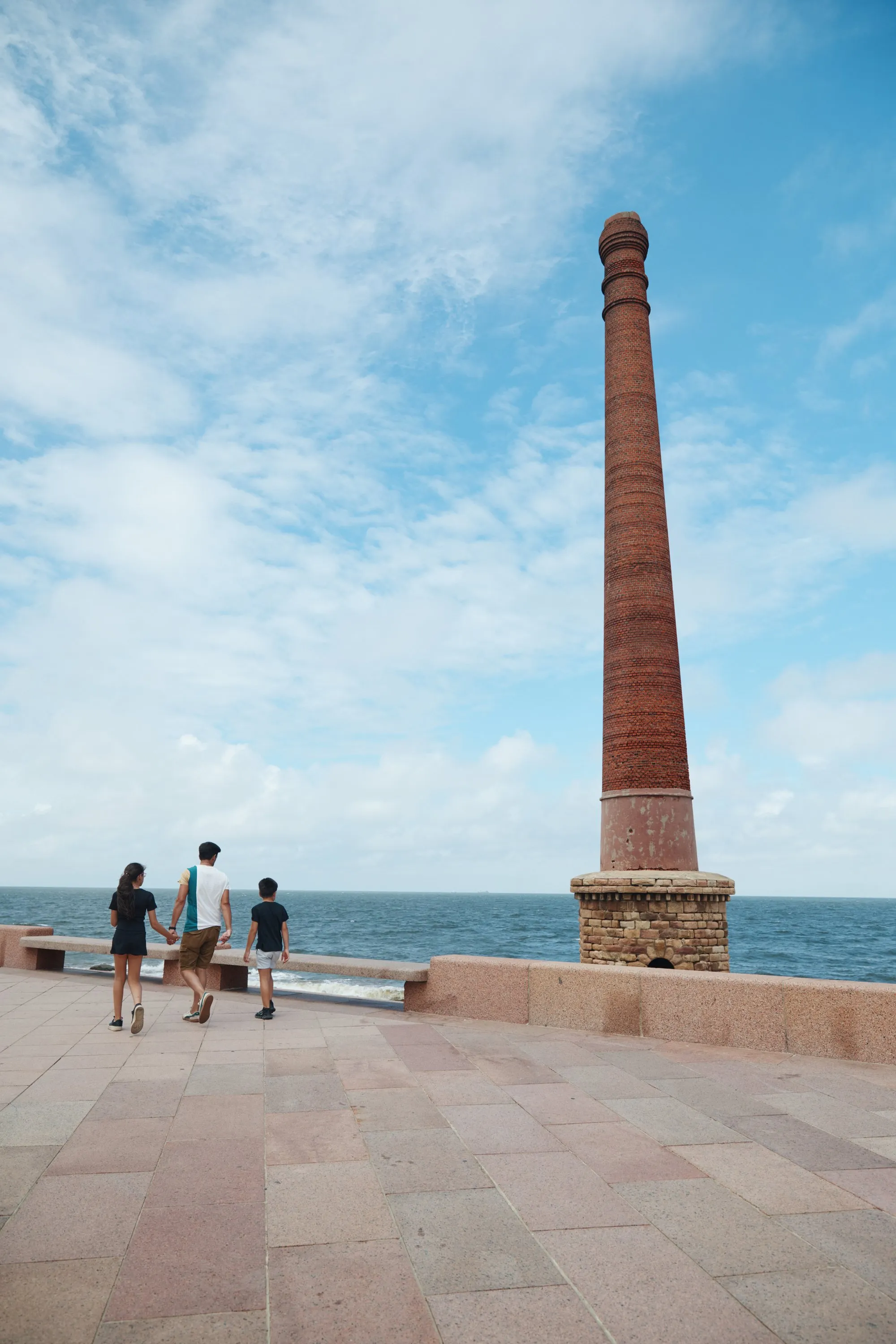 Tres personas mirando el río junto a una vieja chimenea de ladrillo