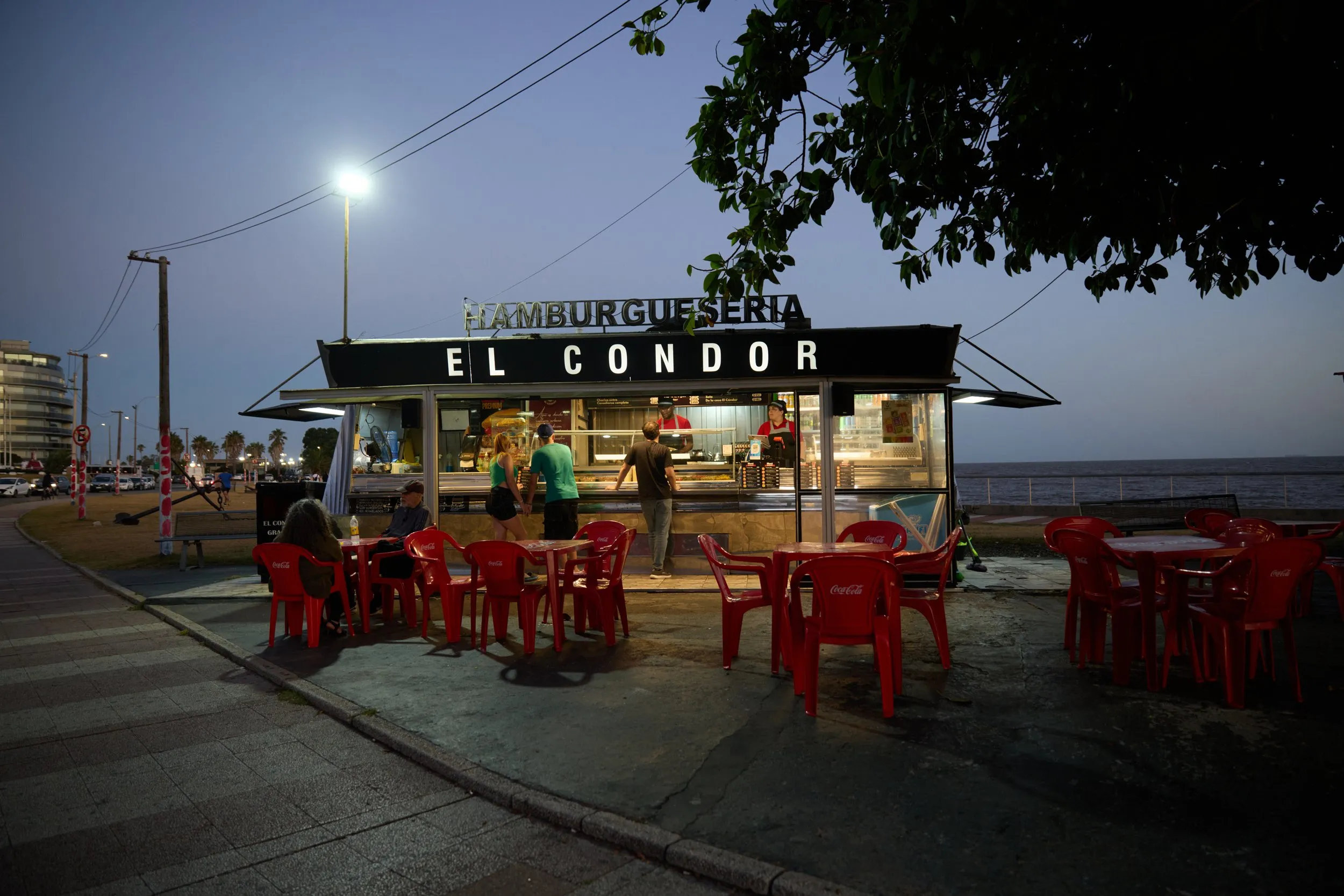 El carrito El Cóndor de noche en la Rambla de Montevideo, con sus sillas rojas vacías