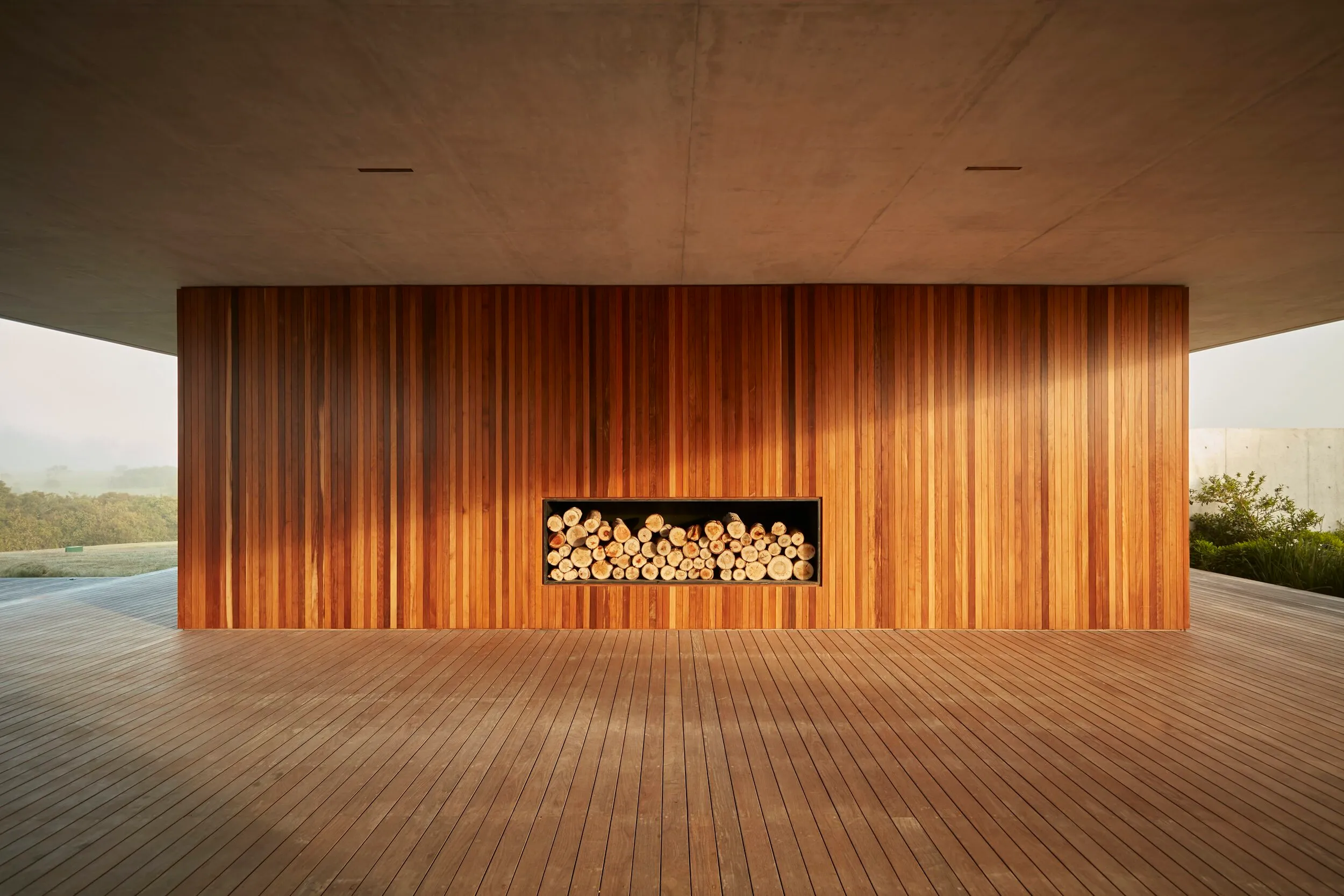 Pared de madera con estante de troncos en un espacio moderno y abierto.
