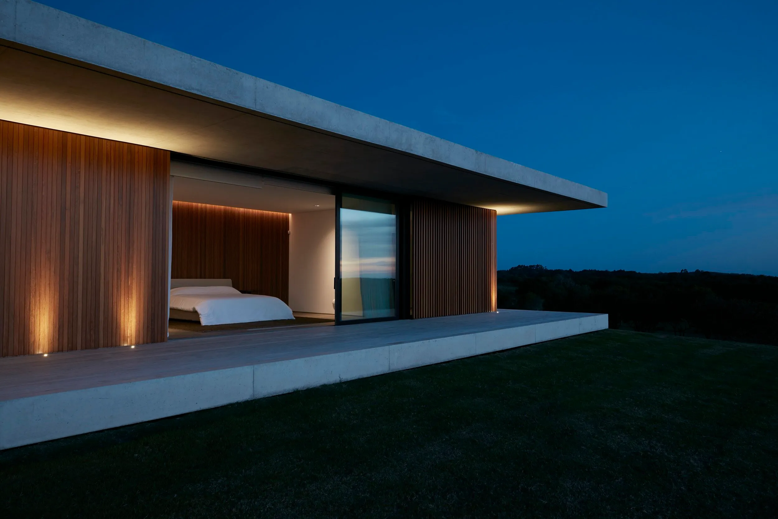Casa moderna con balcón y vistas a la naturaleza durante la noche.