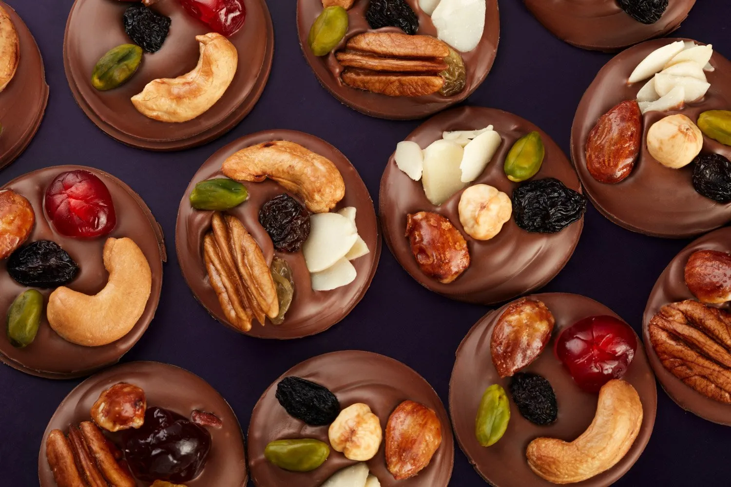 Chocolates artesanales decorados con nueces, almendras, pistaches, pasas y cerezas confitadas.