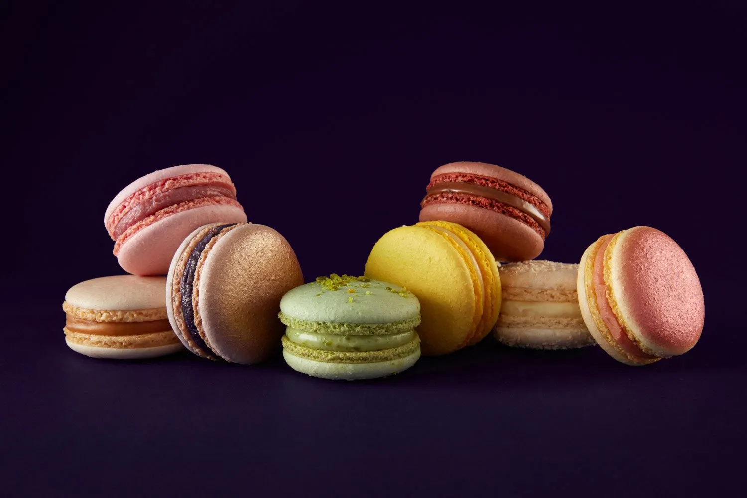 Macarons de diferentes colores y sabores en fondo negro.