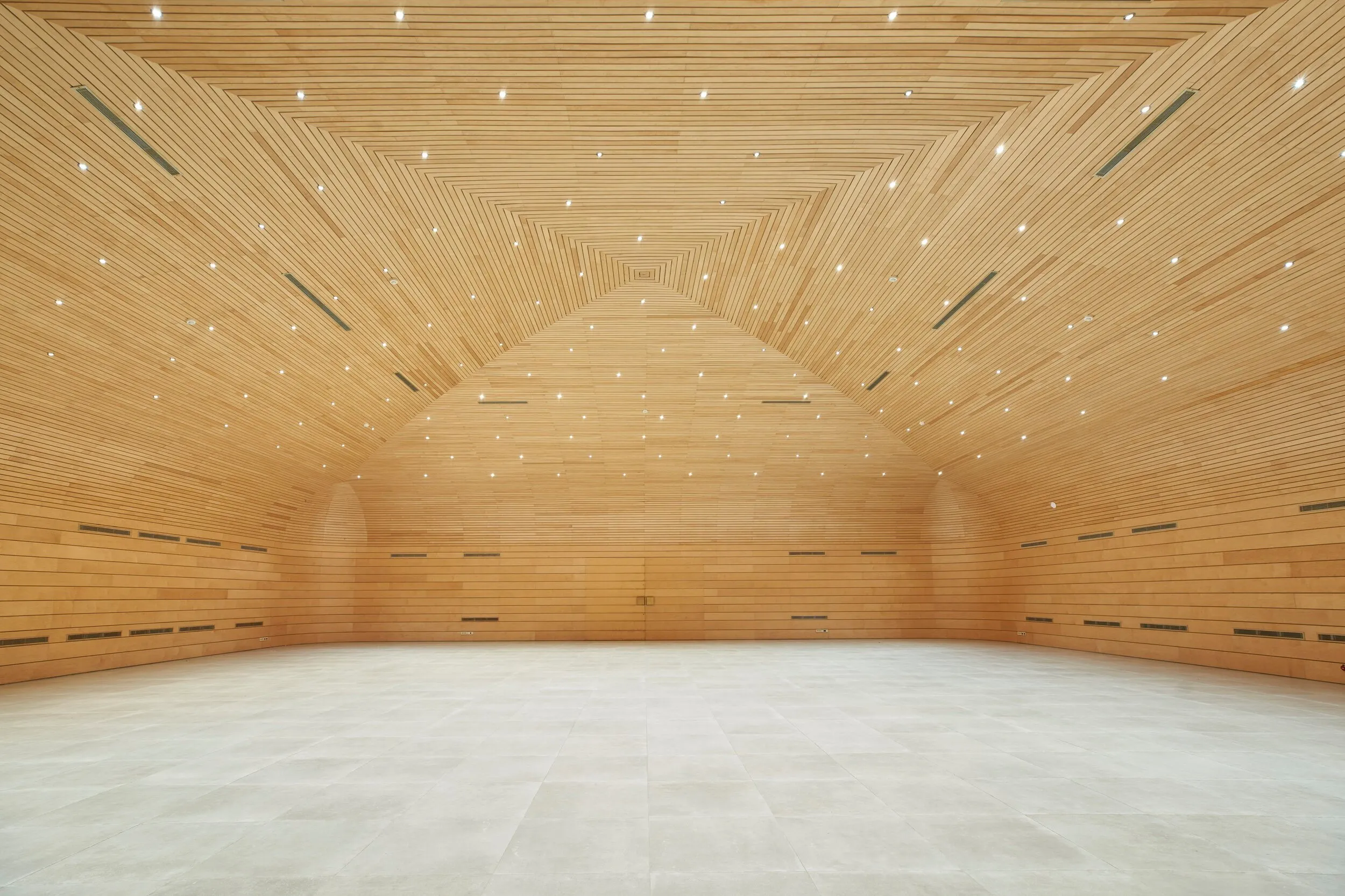 Salón amplio con paredes y techo de madera y piso de baldosas claras.