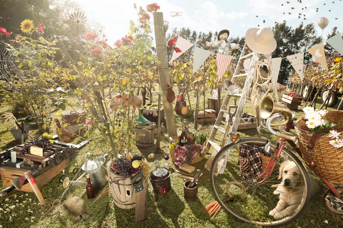 Decoración de campo con limonera, bicicleta con canasta de flores, figuras de animales, banderines, globos y objetos vintage