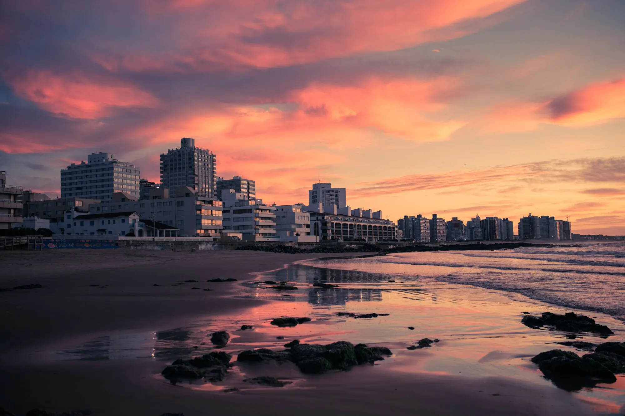 Los edificios de la rambla de Punta del Este al atardecer, reflejados en la arena mojada