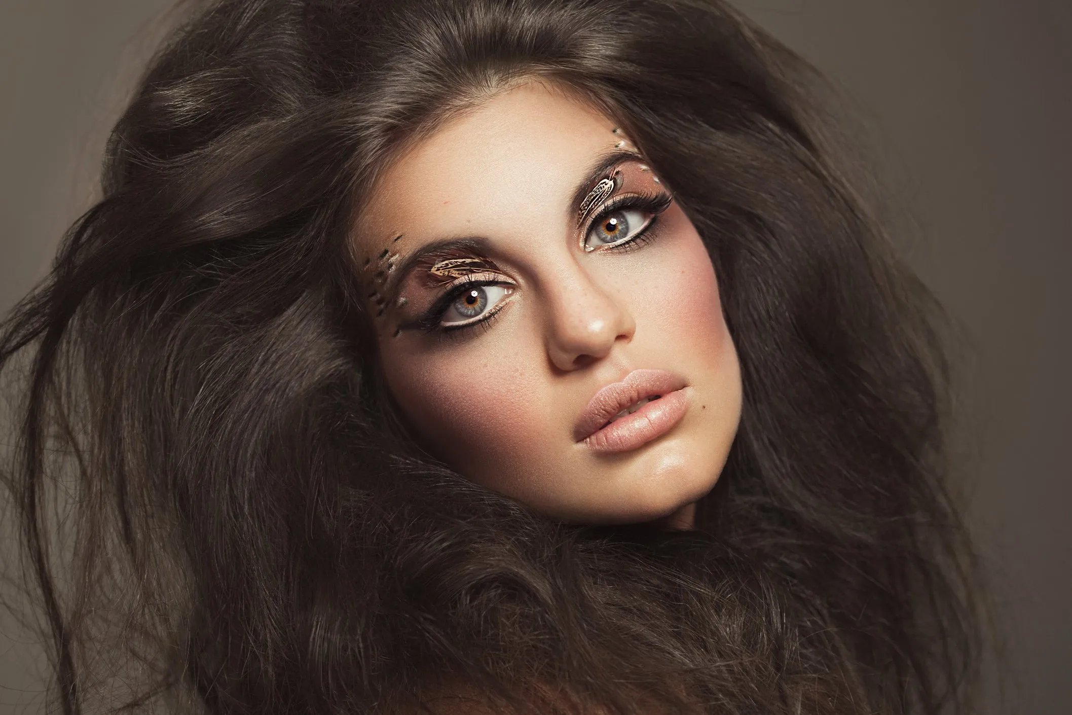 Retrato de una mujer con maquillaje artístico y cabello voluminoso.