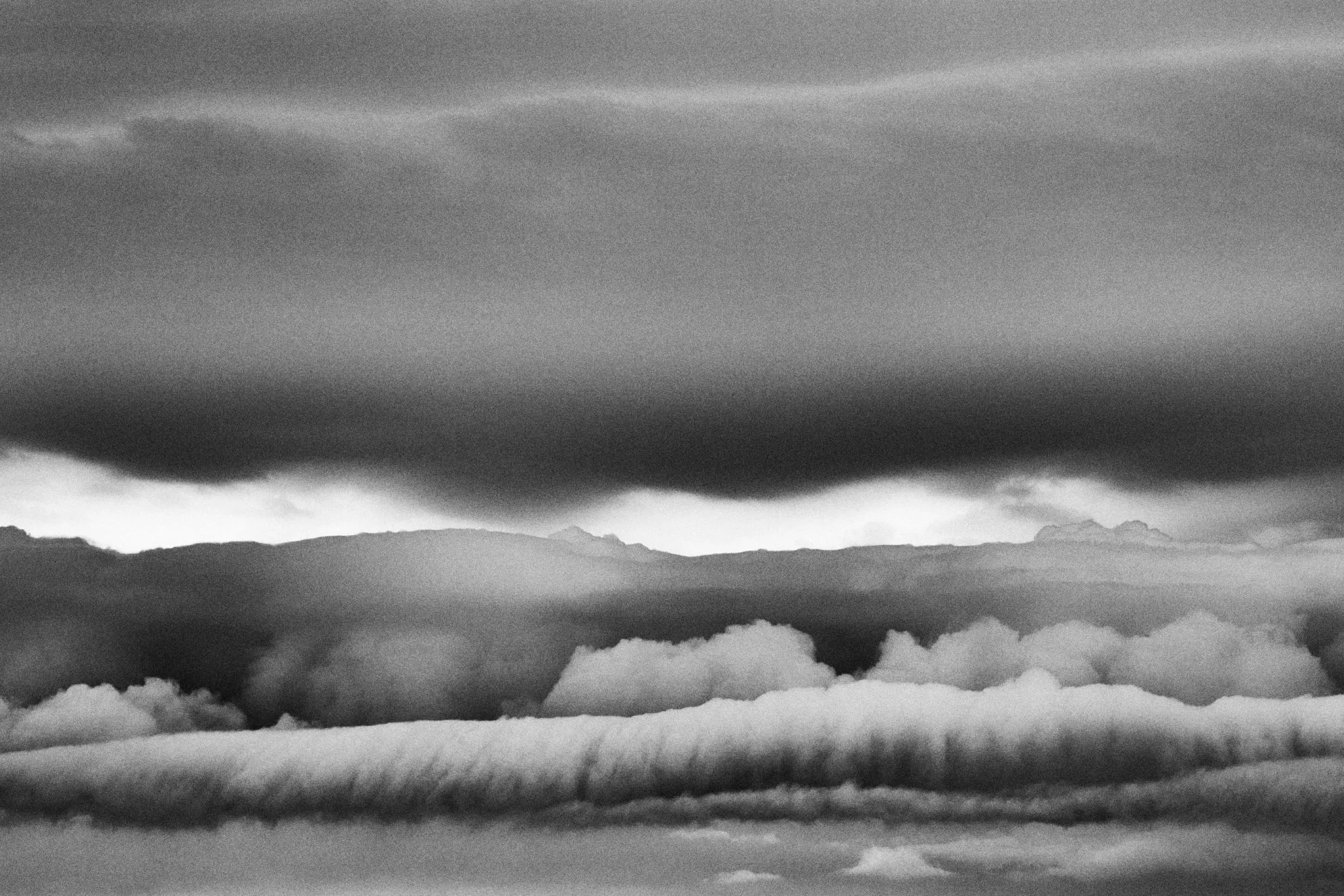 Nubes en capas, una alargada como un cigarro sobre el horizonte, en blanco y negro