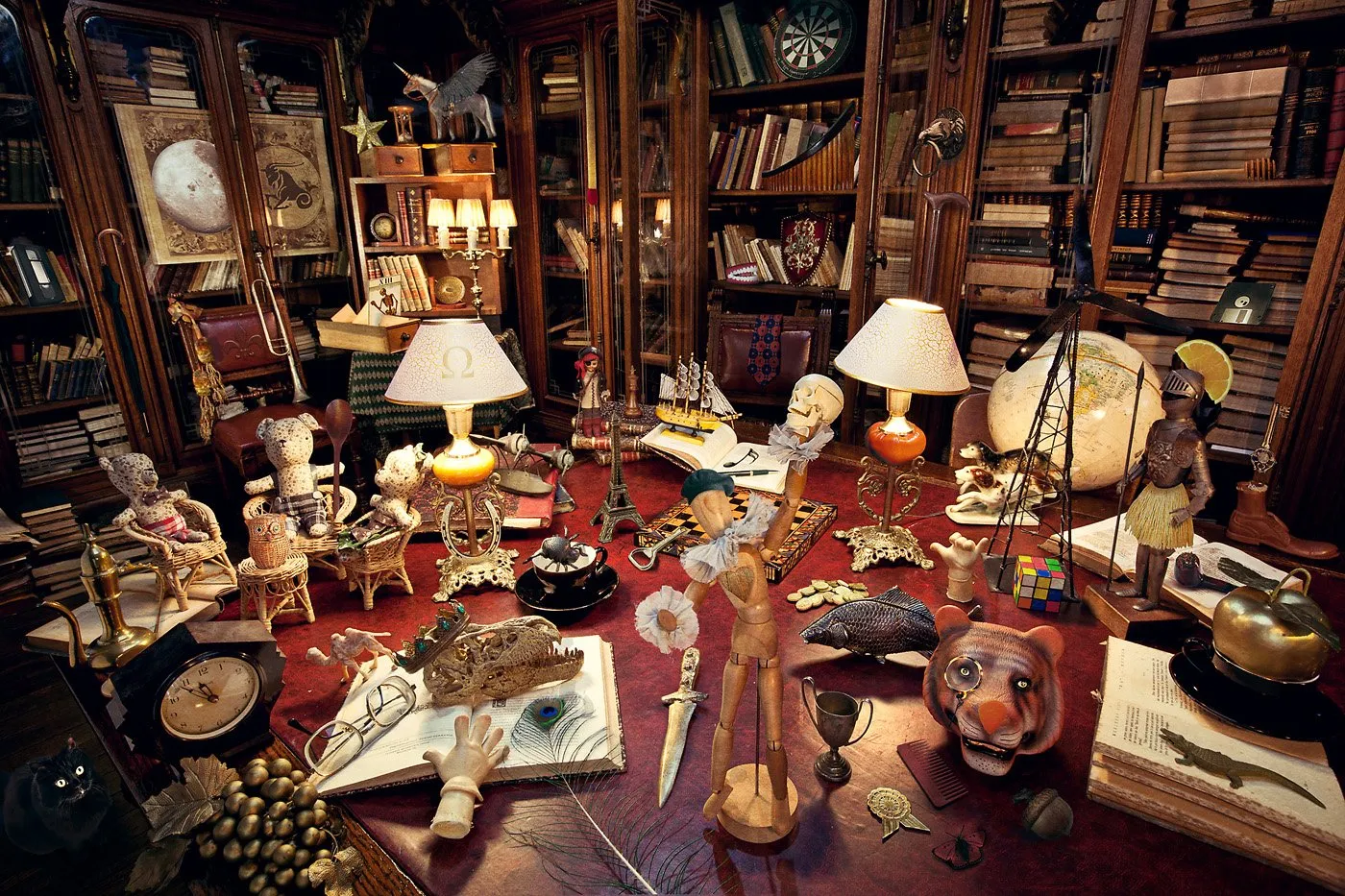 Estanterías llenas de libros, con objetos decorativos y figuras diversas en una oficina o librería antigua.