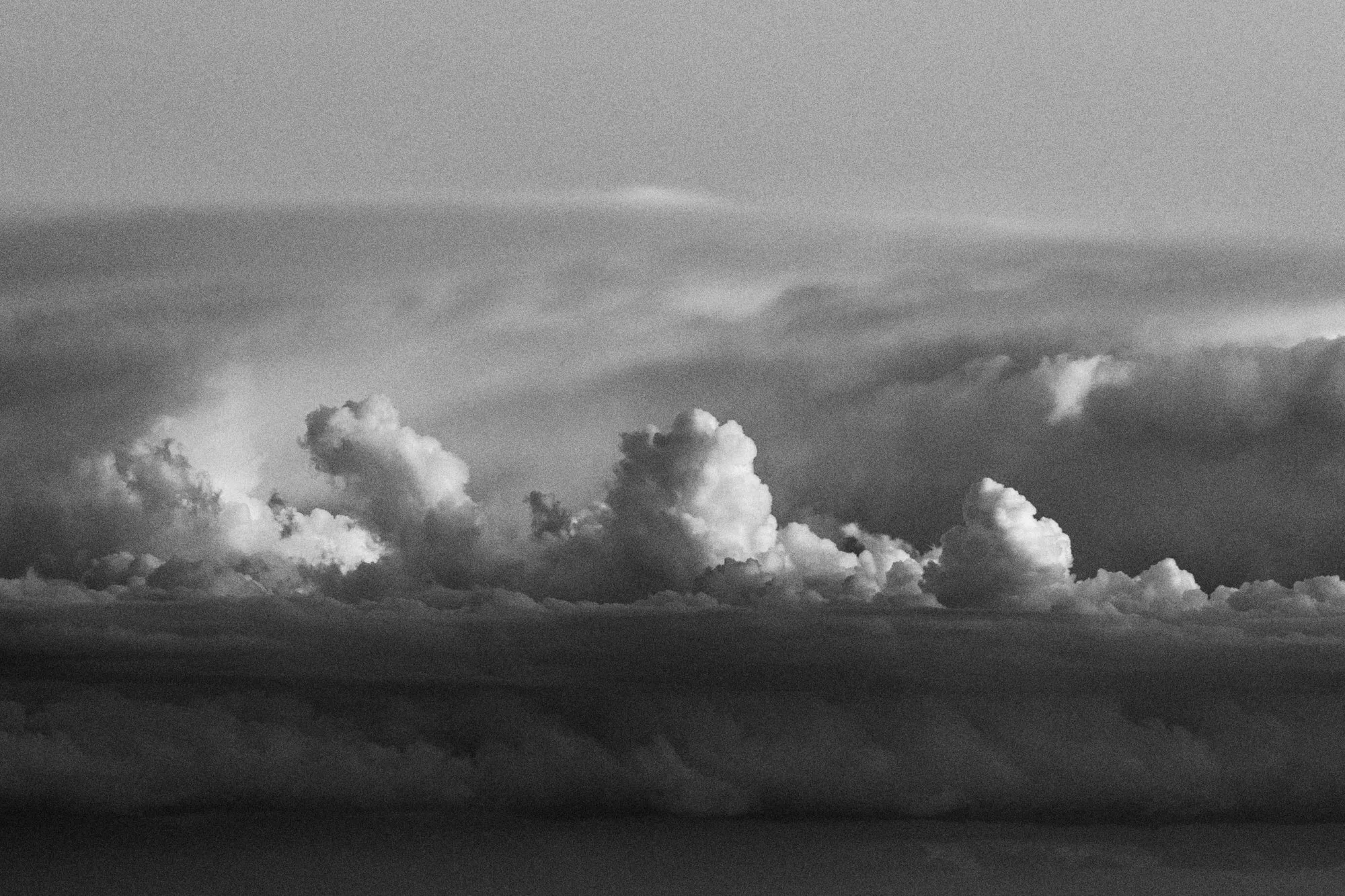 Cúmulos apilados sobre una banda oscura de nubes, en blanco y negro