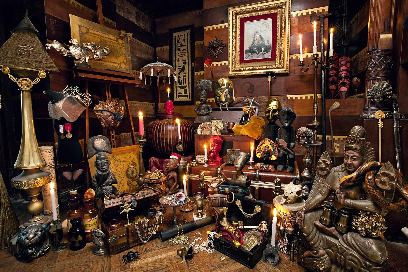 Colección de objetos y artefactos culturales, incluyendo estatuas, cuadros y objetos decorativos en una habitación con paredes de madera.